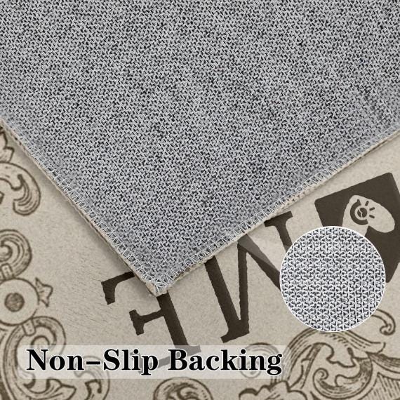 May include: A rectangular rug corner showing a gray textured non-slip backing with a stitched edge. The rug is placed over a beige surface featuring dark brown decorative scrollwork and the text Non-Slip Backing. A circular inset shows the texture.