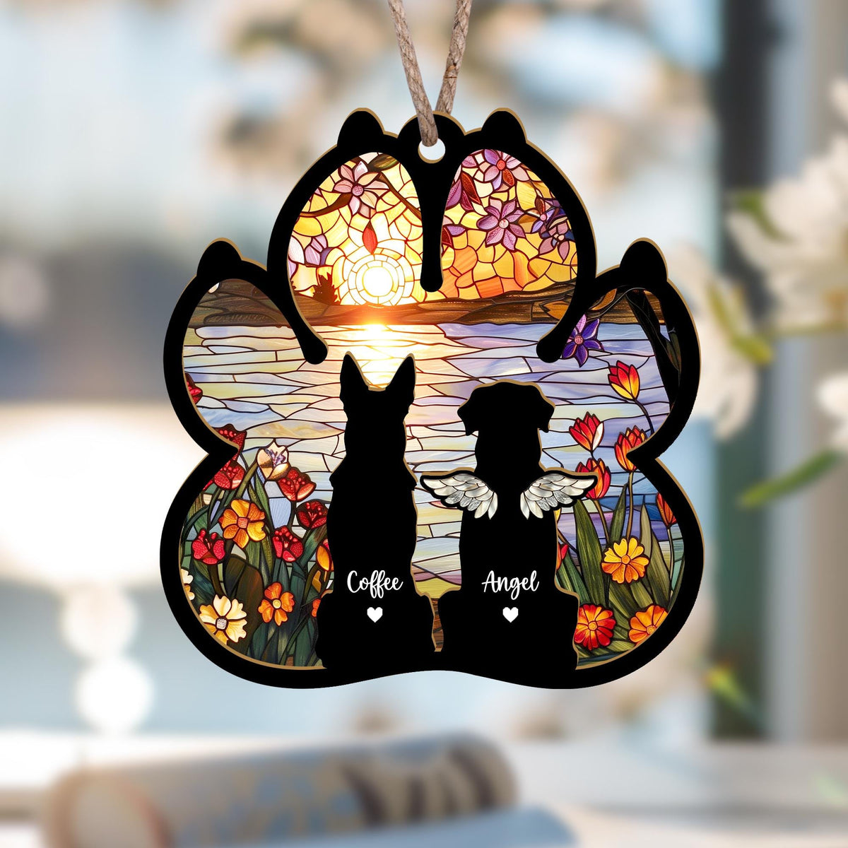 May include: A wooden paw print ornament with a stained glass design of a sunset over a lake. Two dog silhouettes are in the foreground, one with angel wings. The text "Coffee" and "Angel" are below the dogs.