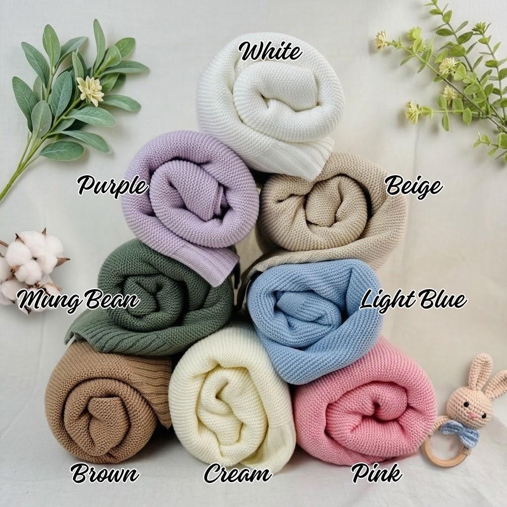 A collection of eight rolled knit fabrics in various colors, labeled as White, Purple, Beige, Mung Bean, Light Blue, Brown, Cream, and Pink. Each fabric features a consistent ribbed texture, arranged in a stacked formation.