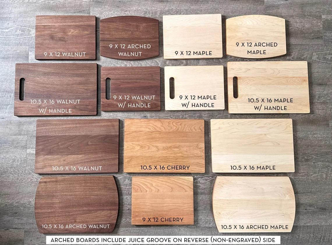 A collection of various wooden cutting boards, each with different sizes and shapes, arranged on a wooden surface.
