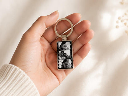 Film strip metal keychain held in hand showing size and shiny epoxy finish with 3 personalized pictures