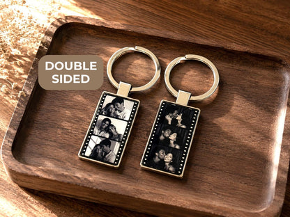 Silver metal film strip keychain with 3 black and white custom photo frames sealed under epoxy coating, shown on white background