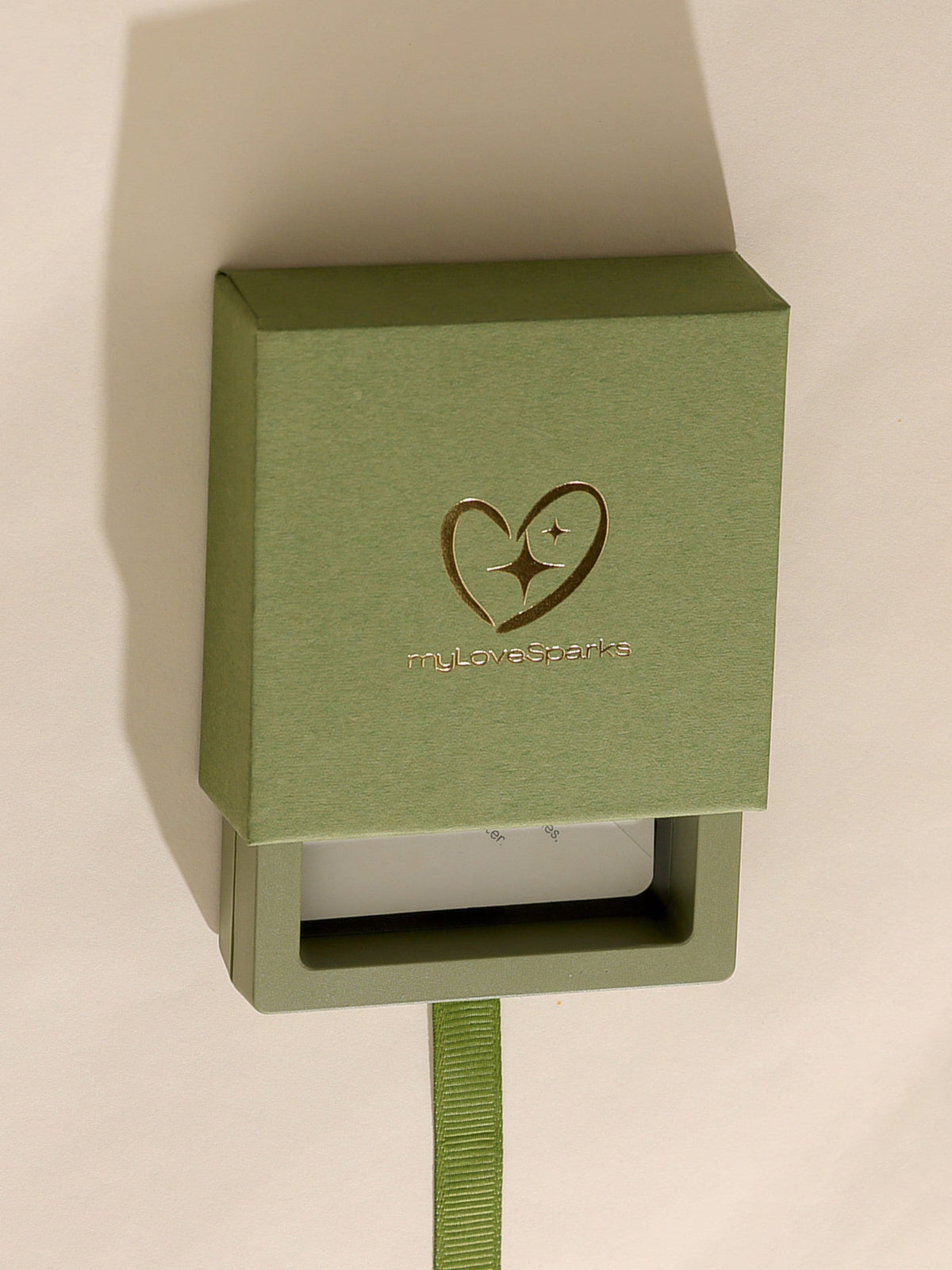 A green gift box with a pull-out drawer. The box has a gold heart and star design with the text "myLoveSparks". A green ribbon is attached to the drawer. The box is on a white background.