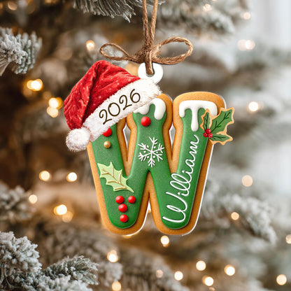 May include: A gingerbread-style letter W Christmas ornament featuring a red Santa hat with the year 2026 printed on the brim. The letter is decorated with green icing, white snowflake details, red holly berries, green leaves, and the name William.