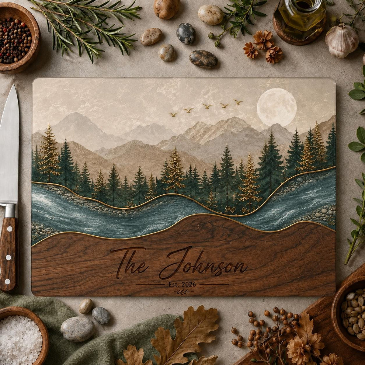 A rectangular cutting board featuring a printed landscape of mountains, a forest of pine trees, a river, and a full moon. The lower section has a wood grain pattern with the engraved text The Johnson Est. 2026.