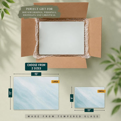 A rectangular tempered glass cutting board with a light blue and white marbled pattern. The large size measures 15 inches by 11 inches, and the small size measures 11 inches by 8 inches. The product is shown inside a cardboard shipping box.