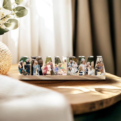 May include: A wooden block with the word "GRANDMA" spelled out in clear acrylic letters. Each letter contains a different family photo. The block sits on a wooden surface, with a blurred background.