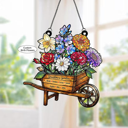 May include: A decorative wooden wheelbarrow filled with colorful flowers, including red roses, white daisies, and blue blossoms. The text "Grandma's Garden" and names are visible. The sign hangs from a chain.