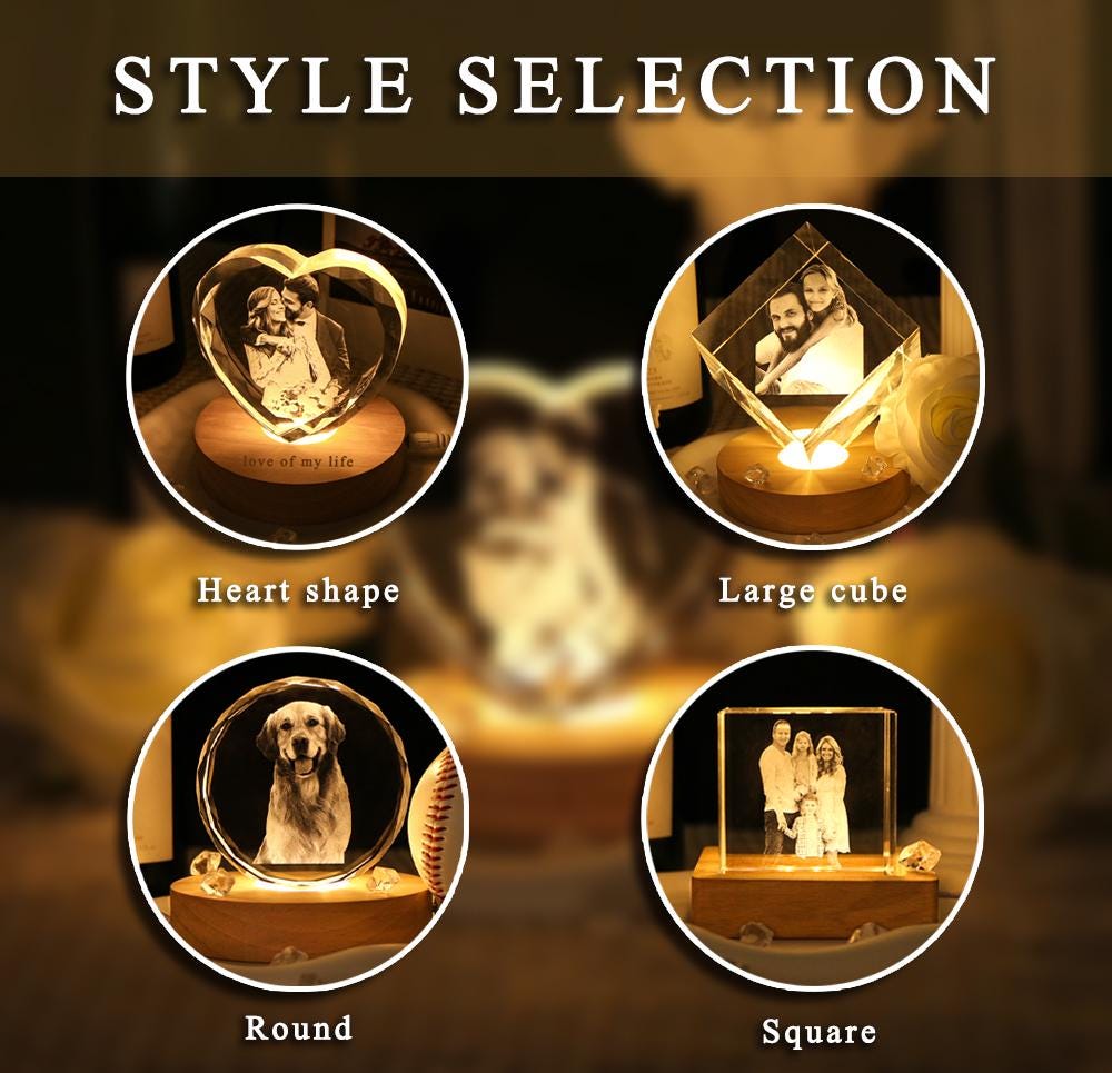 A collection of four illuminated crystal displays labeled STYLE SELECTION. The shapes include a heart, a large cube, a round disc, and a square block, each featuring an engraved photograph and resting on a circular wooden base.