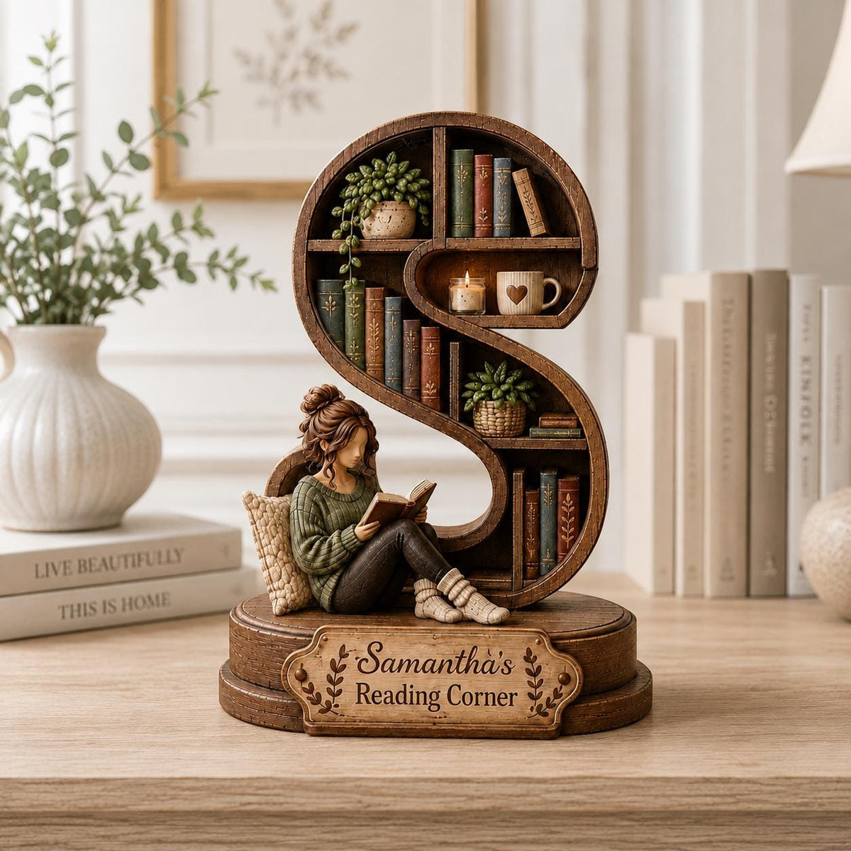 A wooden S-shaped bookshelf figurine featuring a person reading a book while sitting against a pillow. The shelves hold miniature books, a potted plant, a candle, and a mug. A plaque on the base reads, "Samantha's Reading Corner."
