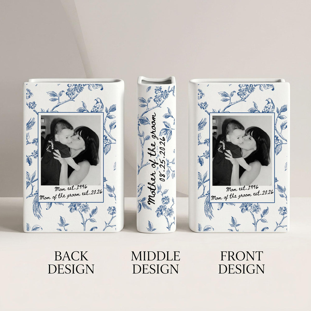 Three white ceramic vases featuring a blue floral pattern. The front and back designs display a black and white photograph of a person holding a child, with the text "Mom est. 1996" and "Mom of the groom est. 2026". The middle vase reads "Mother of the groom 08.25.2026".