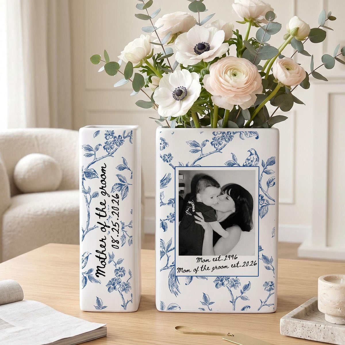Two white rectangular ceramic vases decorated with blue floral patterns. The left vase features the text "Mother of the groom 08.25.2026". The right vase displays a black and white photo of a person holding a child with the text "Mom est. 1996 Mom of the groom est. 2026".
