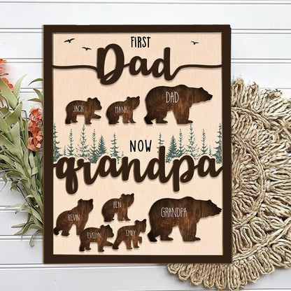 May include: A wooden sign with the text "First Dad Now Grandpa" and a silhouette of a bear family. The bear silhouettes are labeled with names like "Jack", "Hank", "Dad", "Kevin", "Ben", "Evelyn", "Emily", and "Grandpa".