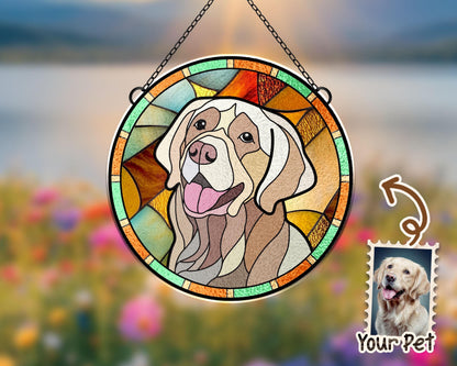 May include: A stained glass window hanging with a colorful design of a dog's head. The dog is a light brown and white color with a happy expression. The window is round and has a metal chain hanging from it.