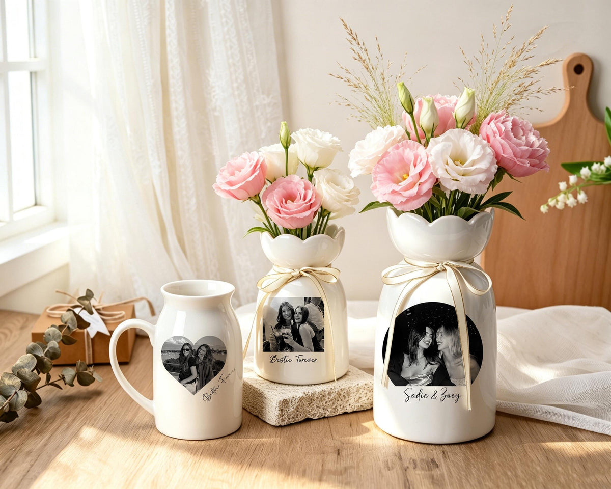 Two white ceramic vases and one matching mug, each featuring a custom black and white photograph and text. The vases have scalloped rims and are tied with cream ribbons, holding arrangements of pink and white eustoma flowers.