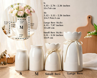 Four white ceramic vases in varying sizes and styles, including two plain cylindrical vases labeled S and M, and two vases with scalloped rims and tied ribbons labeled Small Bow and Large Bow, with dimensions listed in inches and centimeters.