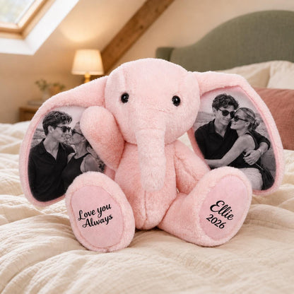 A pink plush elephant toy featuring black and white photographs printed on the inner ears. The left foot pad displays the text Love you Always, while the right foot pad features the name Ellie and the year 2026 in black script.