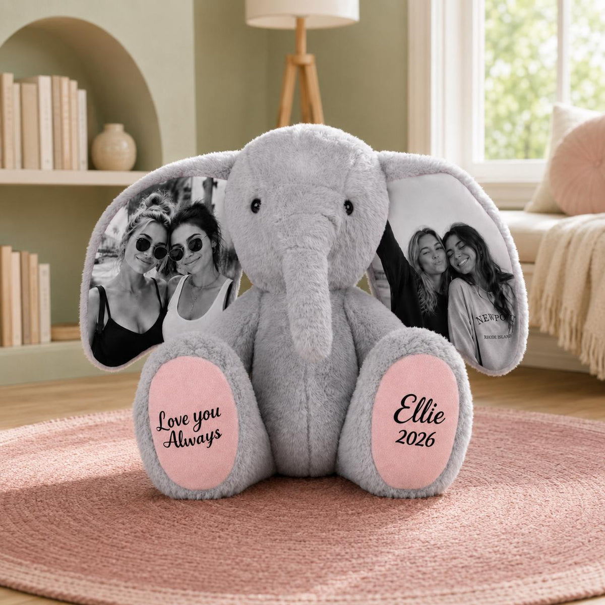 A gray plush elephant toy featuring large ears printed with black and white photographs of two people. The elephant has pink foot pads with black text that reads Love you Always on the left and Ellie 2026 on the right side.