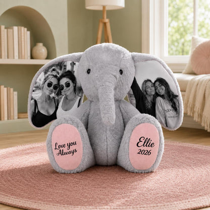 A gray plush elephant toy featuring large ears printed with black and white photographs of two people. The elephant has pink foot pads with black text that reads Love you Always on the left and Ellie 2026 on the right side.
