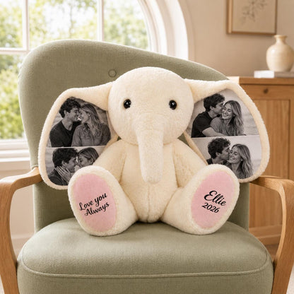 A cream-colored plush elephant toy featuring large ears printed with black and white photographs of a couple. The elephant's pink foot pads are embroidered with the black text "Love you Always" on the left and "Ellie 2026" on the right.