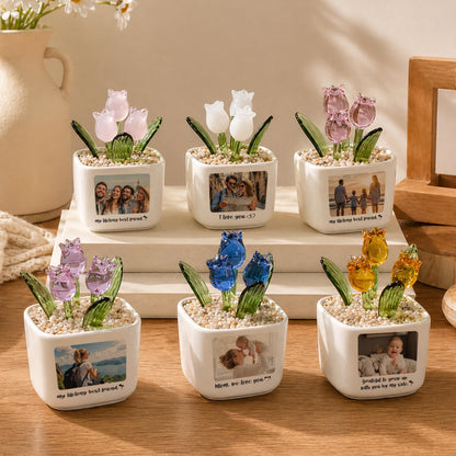 Six small, white ceramic pots, each with a different colored glass tulip arrangement. Each pot has a small photo and a quote. The tulips are pink, white, blue, and yellow. The quotes include "I love you" and "my lifelong best friend."