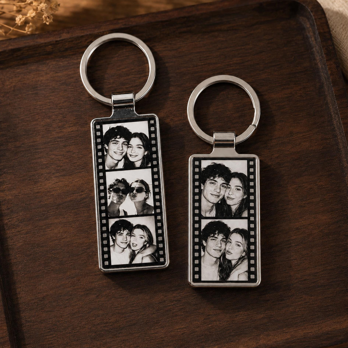 Two rectangular metal keychains featuring a black and white film strip design. Each keychain displays three stacked portrait photographs of a couple. The keychains are attached to circular silver metal split rings for holding keys.