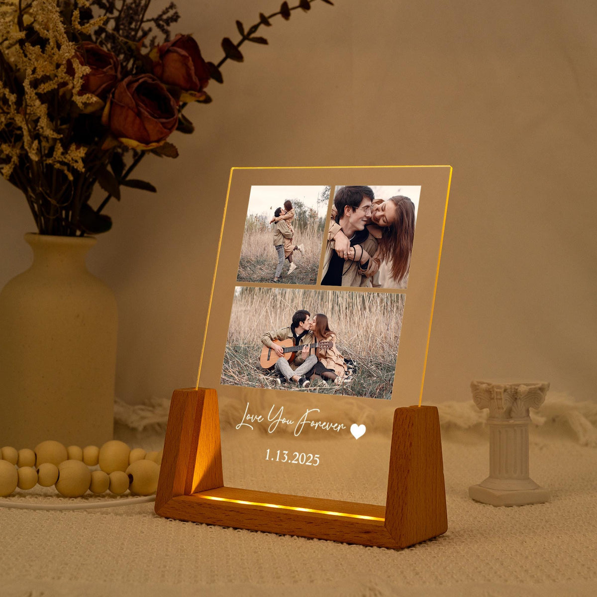 A lighted acrylic photo display with three images of a couple. The display has a wooden base and the words "Love You Forever" and the date 1.13.2025 are etched on the front. The display is lit with a warm glow.