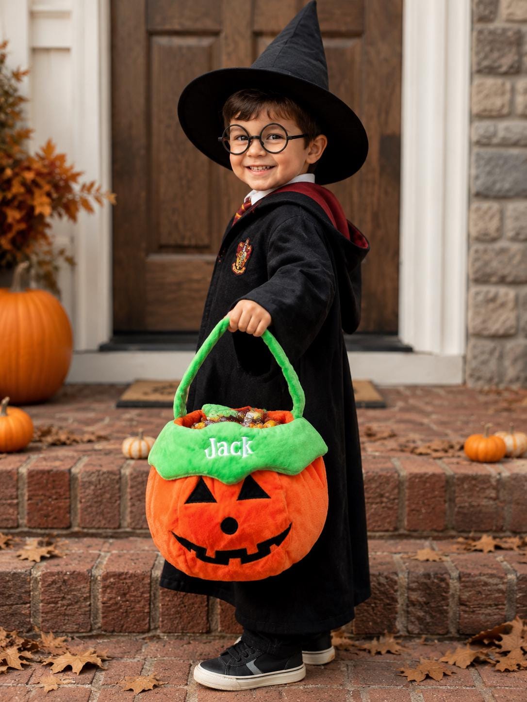 A plush orange pumpkin-shaped candy bucket with a bright green handle and rim. The name Jack is embroidered in white on the green rim. The pumpkin features a black felt jack-o'-lantern face with triangular eyes and a jagged mouth.