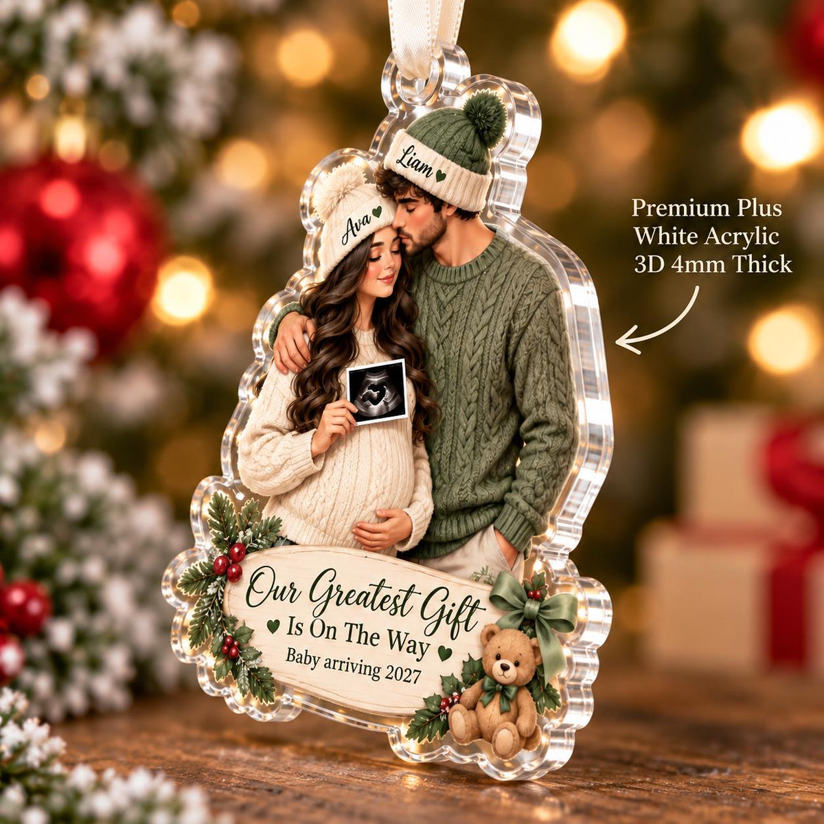 May include: A clear acrylic ornament featuring a couple wearing knit hats and sweaters, holding a sonogram. The ornament includes the text "Our Greatest Gift Is On The Way" and "Baby arriving 2027," decorated with holly, berries, and a teddy bear. It is 4mm thick.