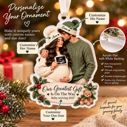 May include: A custom acrylic Christmas ornament featuring a couple wearing knit hats and sweaters, holding an ultrasound image. The ornament includes the text 'Our Greatest Gift Is On The Way' and 'Baby arriving 2027', decorated with pine branches, red berries, and a teddy bear.