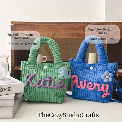 Two corduroy tote bags, one green with lavender yarn and the name "Katie", the other blue with rose yarn and the name "Avery". Each bag has a handle, a button, and a small charm. TheCozyStudioCrafts.