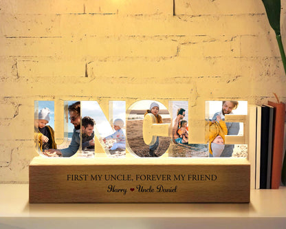 May include: A wooden light-up sign with the word "UNCLE" spelled out in large letters. Each letter has a photo of a different person inside. The sign has a wooden base with the text "First my uncle, forever my friend. Harry Uncle Daniel".