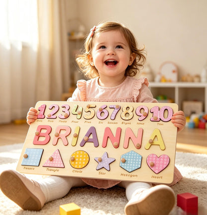 A rectangular wooden puzzle board featuring the name BRIANNA in large, colorful, patterned letters, a row of numbers from one to ten, and a row of geometric shapes including a square, triangle, circle, star, hexagon, and heart.