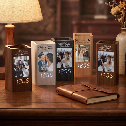 Five rectangular wooden desk organizers with integrated digital clocks. Each unit features a vertical photo display, personalized engraved names, and a glowing digital time display showing 12:05 in white or orange light.