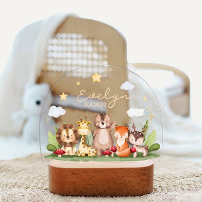 May include: A clear acrylic night light with a wooden base. The light features a whimsical woodland scene with a lion, giraffe, bear, fox, and deer. The text "Evelyn 5.4.2023" is printed on the light.