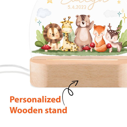 May include: A white acrylic night light with a woodland animal theme. The light features a lion, giraffe, bear, fox, and deer. The light is on a wooden stand with the date 5.4.2023 printed on the light.  Personalized wooden stand.